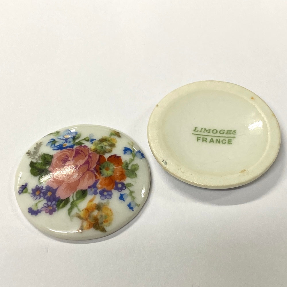 Two ceramic vintage discs, one with floral design and 'Limoges France' text on the other.