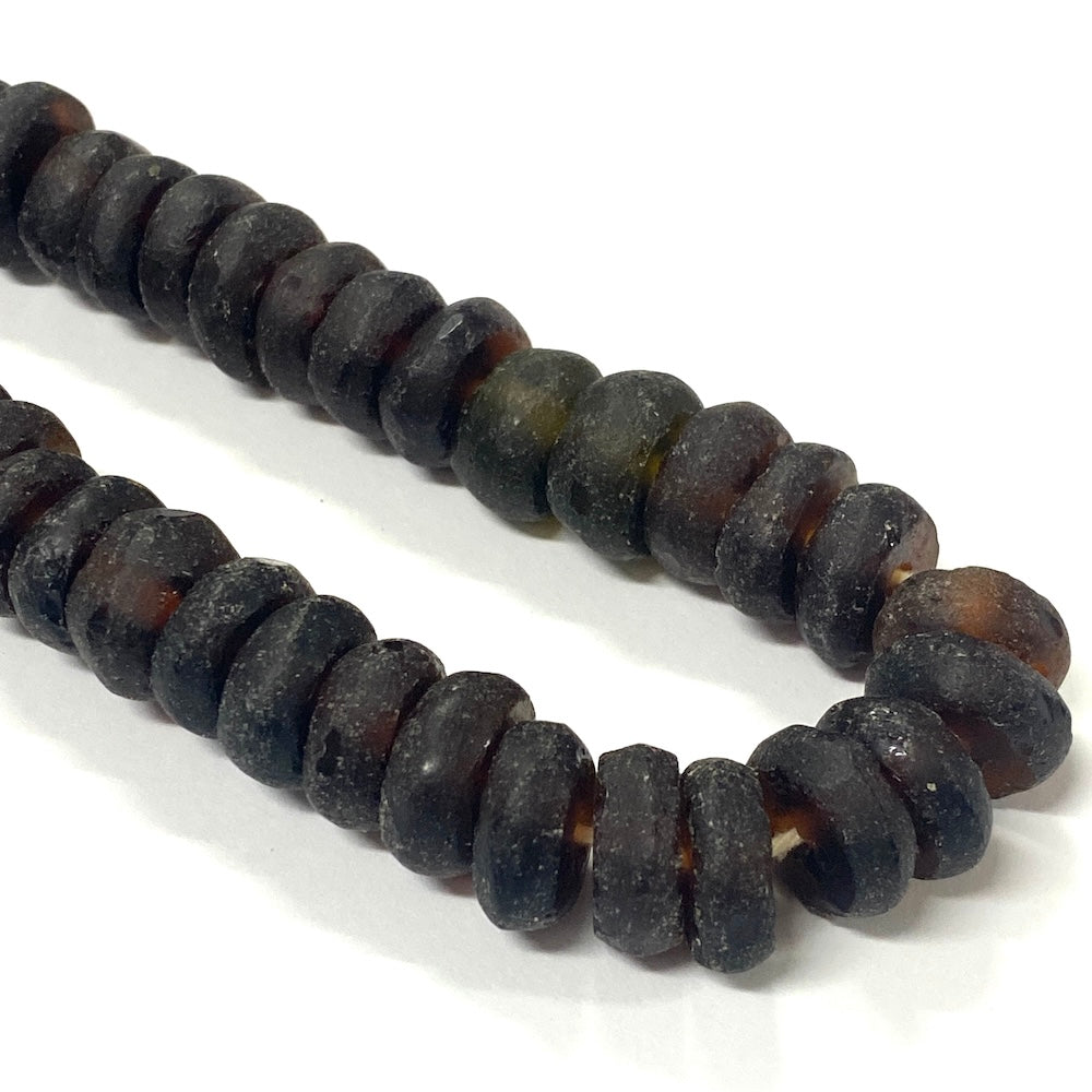 Close-up of dark brown recycled glass beads on a white background
