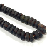Close-up of dark brown recycled glass beads on a white background