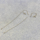 Silver earring hooks and threaders on a gray surface