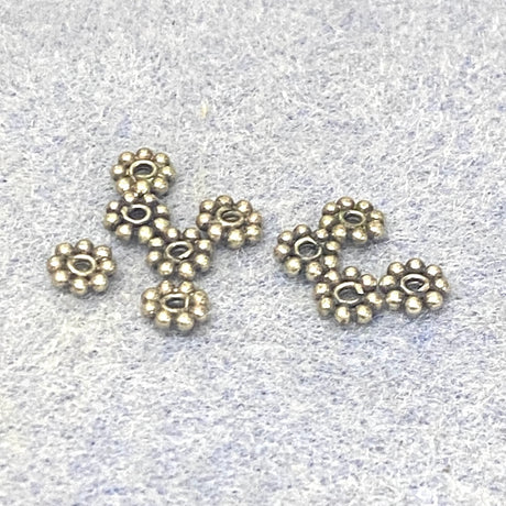 Sterling Silver floral daisy spacer beads on a light gray background