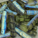 Collection of glass cylindrical minaret prayer beads with star patterns on a gray surface