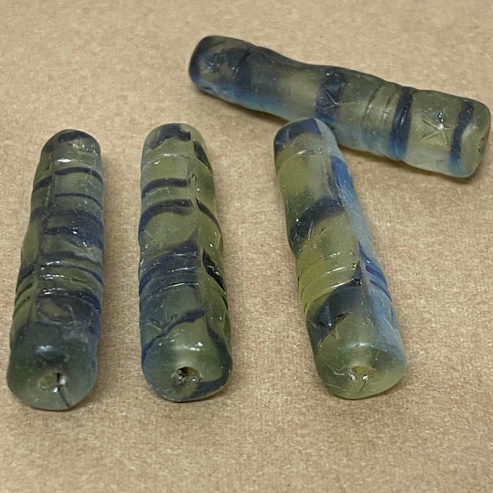 Four striped glass beads on a beige surface