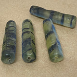 Four striped glass beads on a beige surface