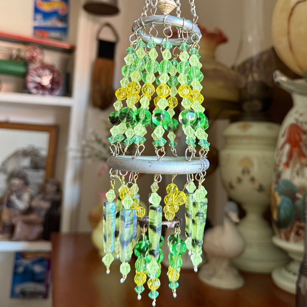 Decorative wind chime with vaseline uranium green and yellow beads hanging indoors.