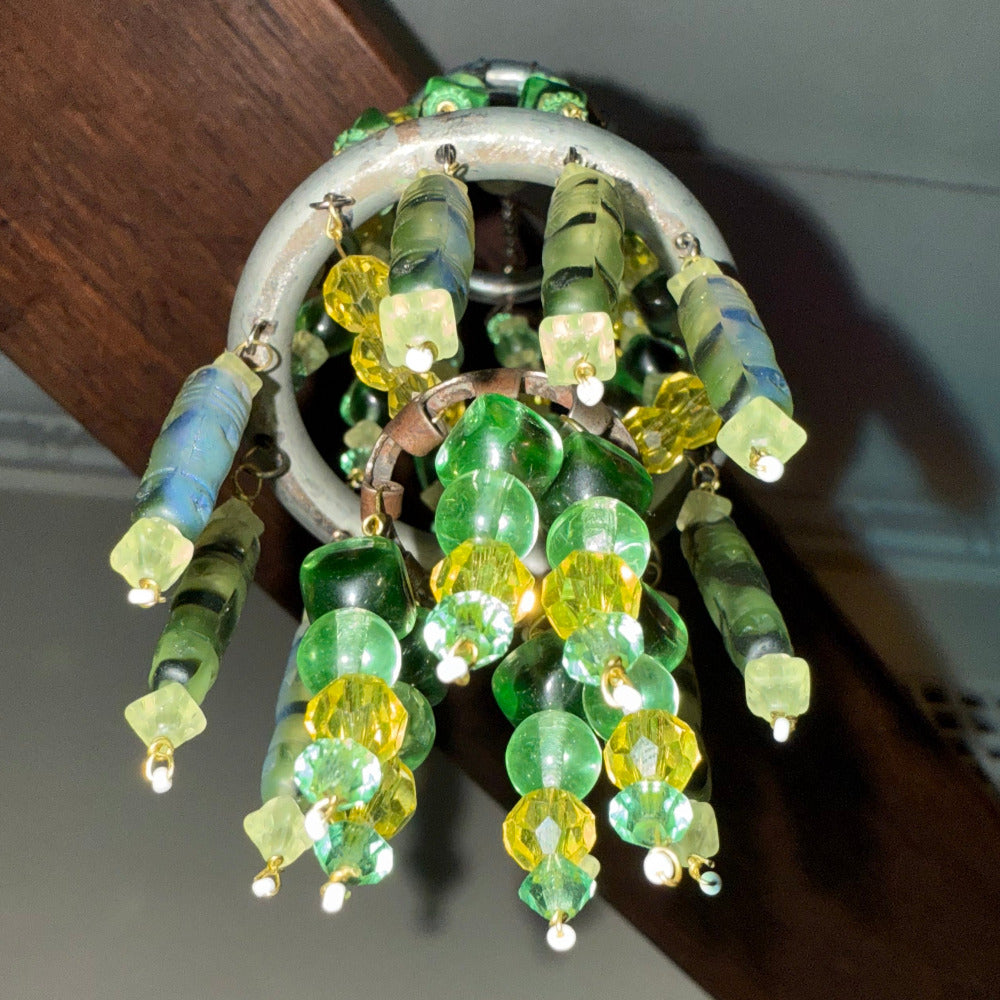 Decorative chandelier with green and yellow glass beads hanging from a ceiling.