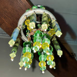 Decorative light fixture with green and yellow beads hanging from a ceiling.