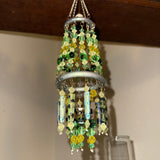 Decorative beaded hanging ornament on a wooden shelf with containers in the background.