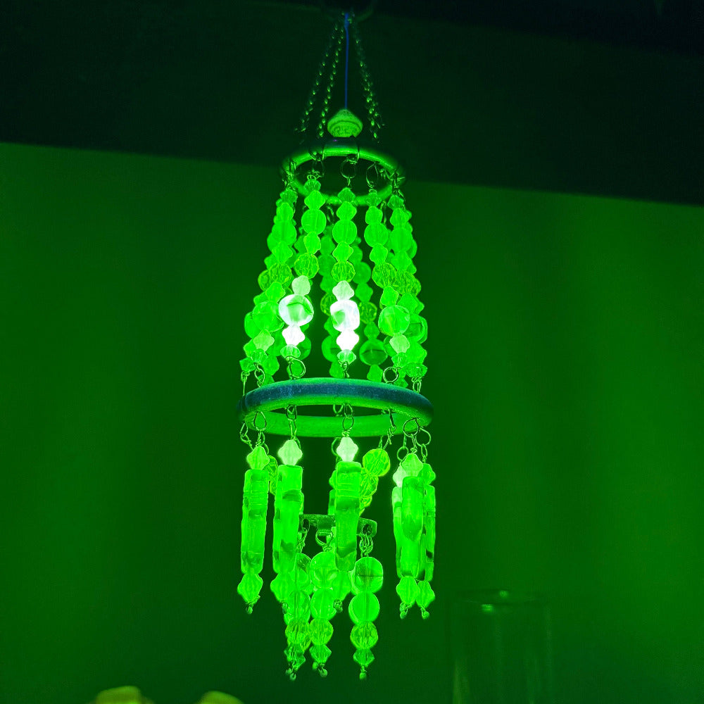 Glowing green chandelier against a dark background under black light