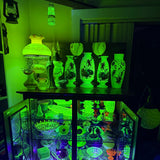 Collection of glowing ceramic items on a shelf in a dark room.