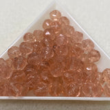 Clear pink glass beads in a triangular container on a light background