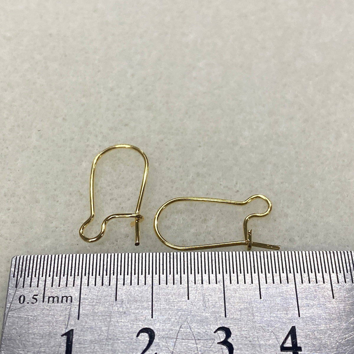 Gold earring hooks on a ruler for size reference
