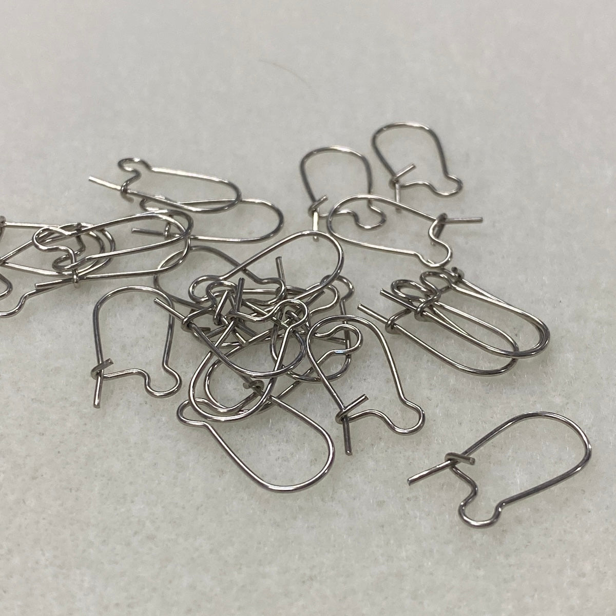 Silver earring hooks on a light gray surface