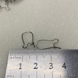 Metal ear hooks with a ruler for scale on a gray background