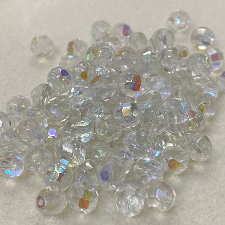 Clear fire polish crystal glass beads with iridescent flash on a light gray background