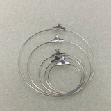 Set of five graded sized metal ear hoop earring fittings with clips on a gray background