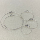 Set of five graded sized metal ear hoop earring fittings with clips on a gray background