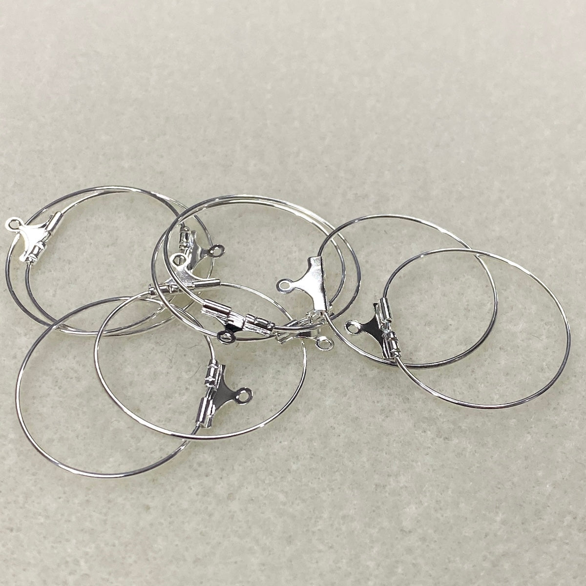 Set of silver hoop earrings on a light gray background