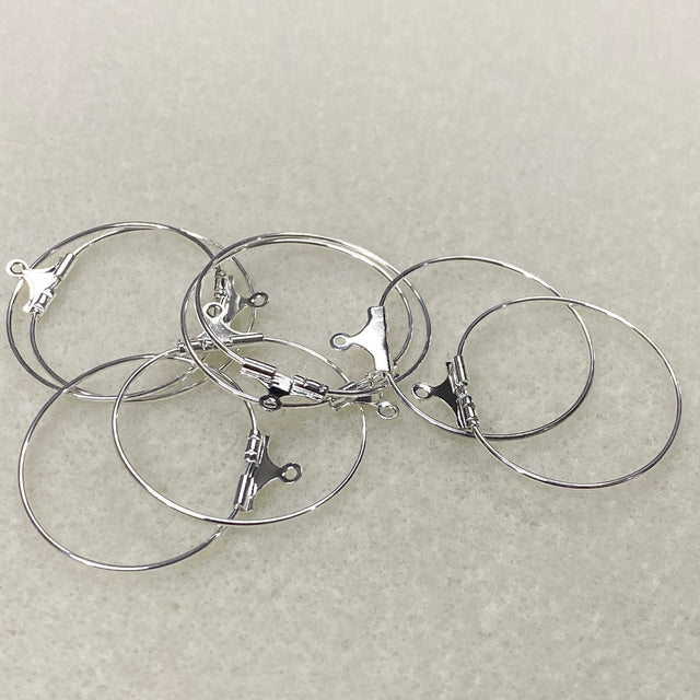 Set of silver hoop earrings on a light gray background
