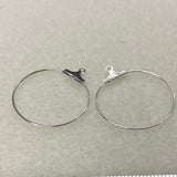 Two silver hoop earrings with clips on a light gray background