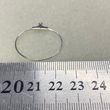 Silver hoop ear ring on a metal ruler with measurements