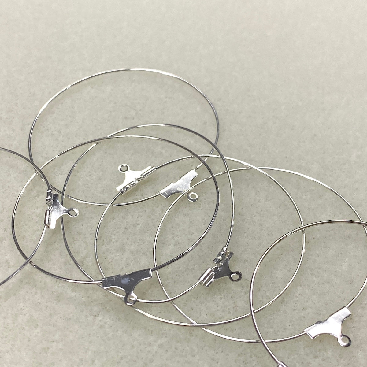 Silver ear hoop fittings with clasp on a light gray background