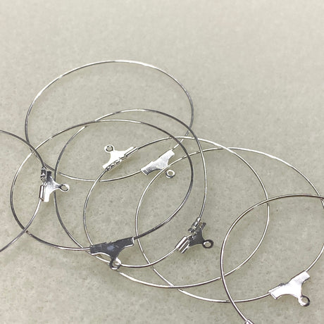 Silver ear hoop fittings with clasp on a light gray background