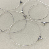 Silver wire ear loop fittings with clasp ends on a beige background