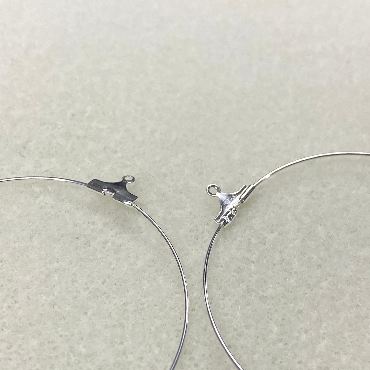 Close-up of silver hoop earrings on a light gray background