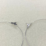 Close-up of silver hoop earrings on a light gray background