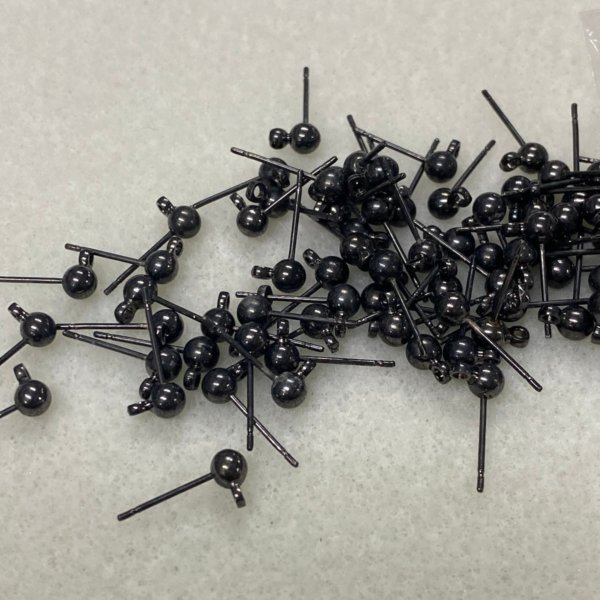 Collection of black jewelry ear stud components on a light gray background