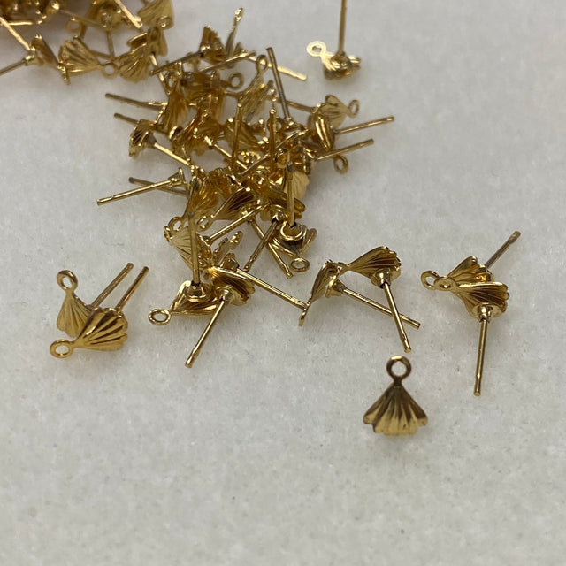 Gold earring components with shell fan design on a light gray background