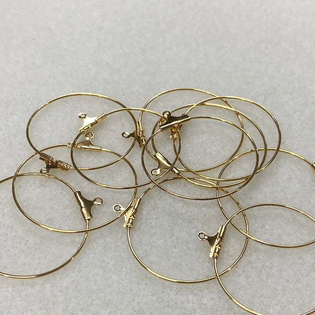 Gold hoop earrings with clasps on a light gray background