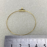 Gold ear loop fitting on a light gray background with a ruler for scale.