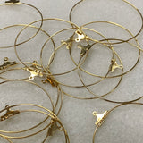 Gold hoop earrings with clasp mechanisms on a light gray background