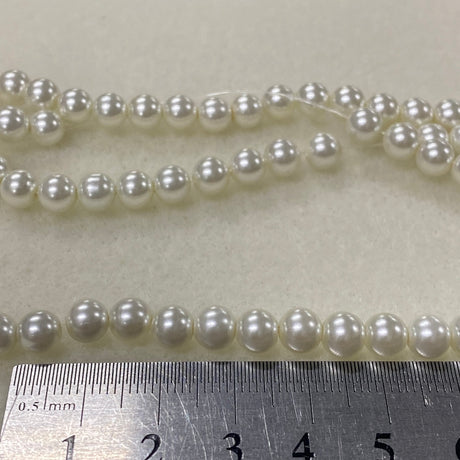 Two strands of pearls with a ruler for scale on a light gray background