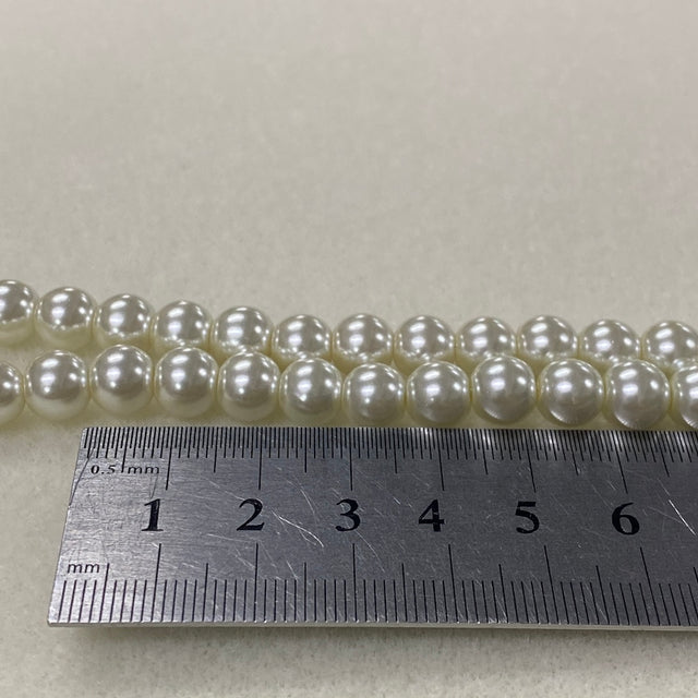 String of pearls with a ruler for size reference on a light gray background