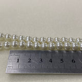 String of pearls with a ruler for size reference on a light gray background
