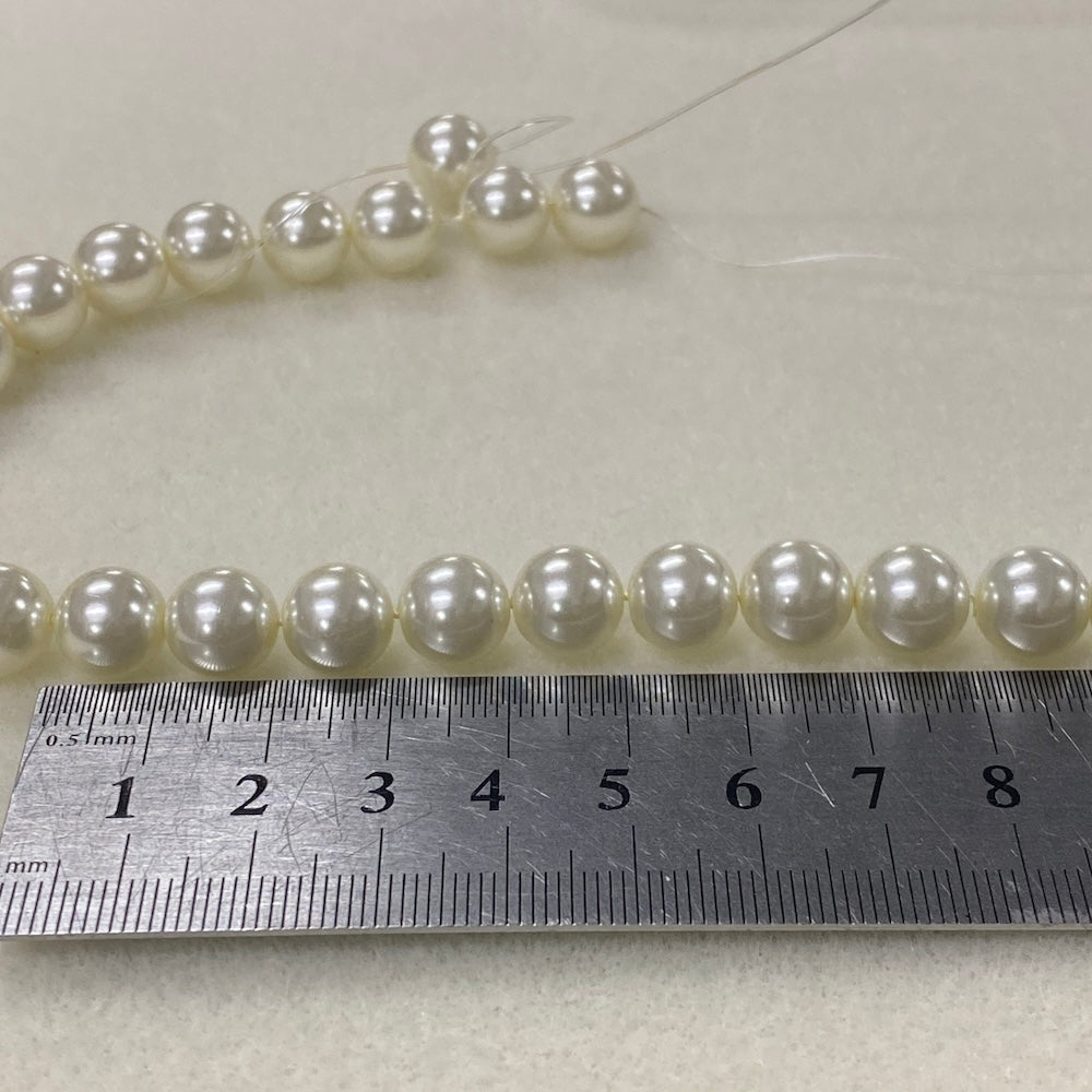 Pearl necklace with a ruler for scale on a light background
