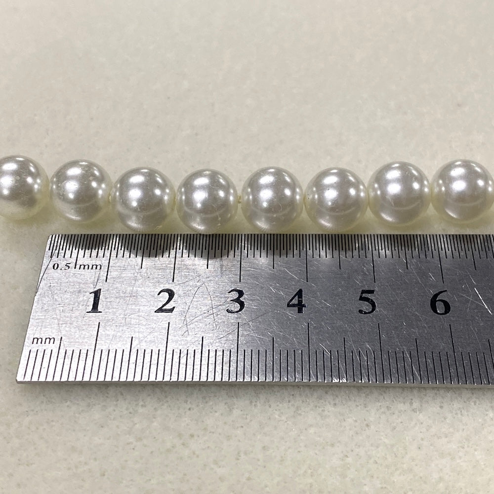 Row of pearls with a metal ruler for scale on a light background