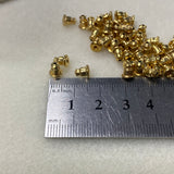 Gold bullet ear stud backs with a ruler for scale on a light gray background