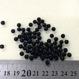 Black beads on a white background with a ruler for scale