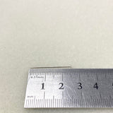 one headpin against Metal ruler on a textured beige surface