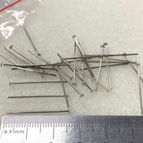 Metal pins with a ruler for scale on a textured surface