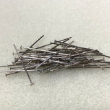 Pile of metal beading head pins on a textured white surface