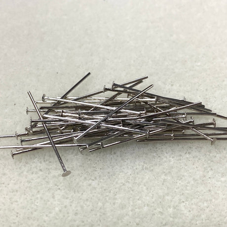 Pile of metal beading head pins on a textured white surface