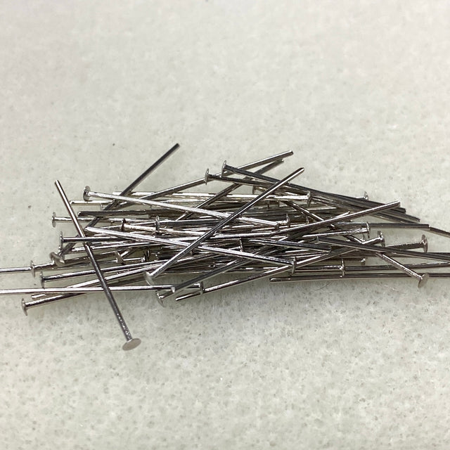 Pile of metal beading head pins on a textured white surface