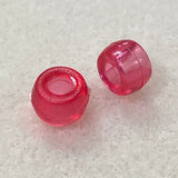 Two pink transparent beads on a textured gray surface