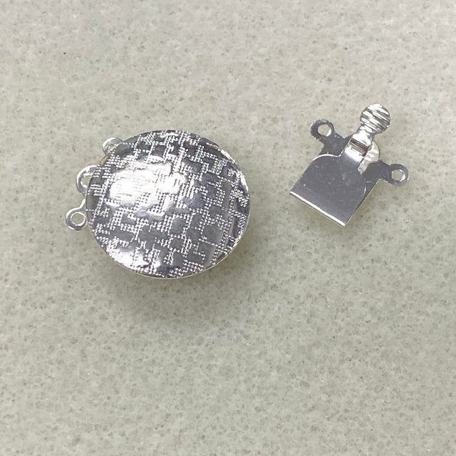 Two halves of a silver metal clasp on a beige background