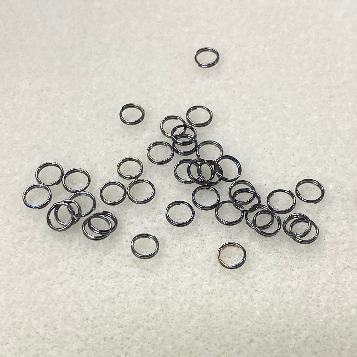 Collection of small metal connector rings on a textured white surface
